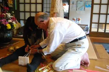 <p>เจ้าของบ้านพักผู้ใจดี ฮัตซึมิ ซาซากิสาธิตวิธีการทำรองเท้าโซริ</p>