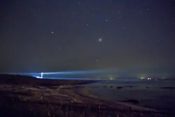 <p>A night-light illuminates the beach, but the stars still shine bright on sparsely-populated Tsunoshima</p>